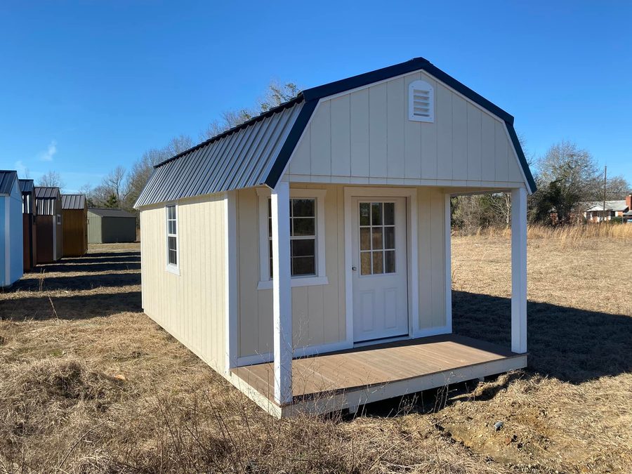 Cream lofted shed with a dark roof and covered porch