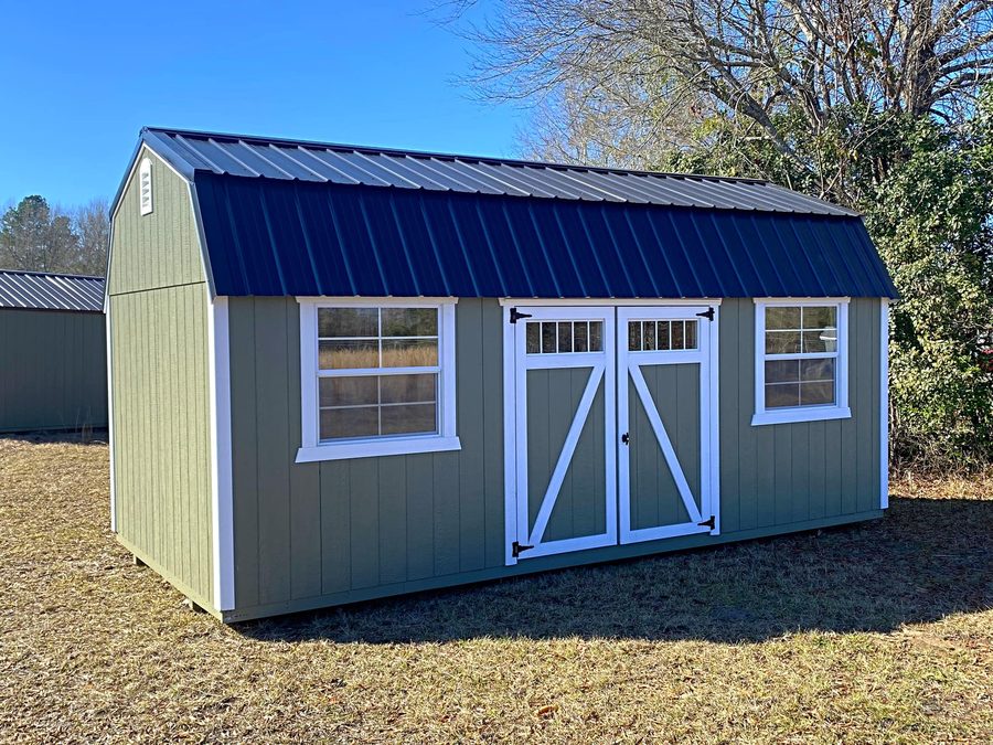 Sage-green lofted barn with a navy roof and white doors