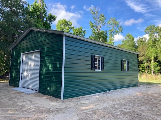 Green steel garage with a white roll-up door and walk-in door